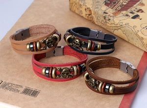Detail of four retro leather bracelets featuring bronze skull charms and wooden beads