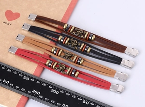 Detailed view of four multilayer leather bracelets with skull charms and steel ruler for scale