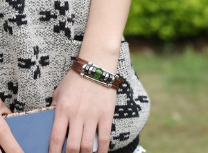 Macro detail of multi-layer vintage leather bracelet with green beads and silver accents