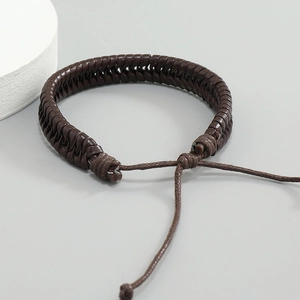 Handmade woven dark brown leather bracelet with adjustable cord on stone background