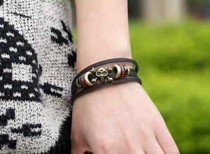 Close-up of punk leather bracelet featuring a bronze skull and dark wooden beads on wrist