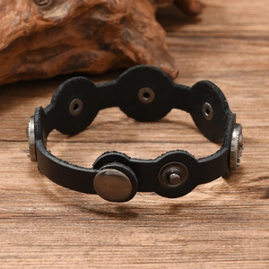 Détail du bracelet en cuir noir avec clous tête de mort vintage et boutons pressions