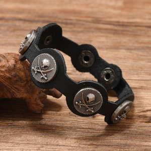 Détail d'un bracelet punk en cuir avec des clous argentés à tête de mort et os