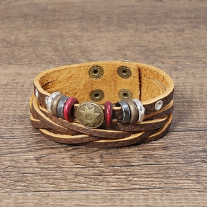 Close-up of brown leather multi-layer woven bracelet with a vintage bronze star emblem