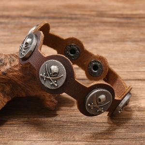 Gros plan du bracelet en cuir marron vintage avec rivets de crâne de pirate en métal