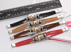 Close-up of multilayer braided leather bracelets in black, brown, and red with metal beads