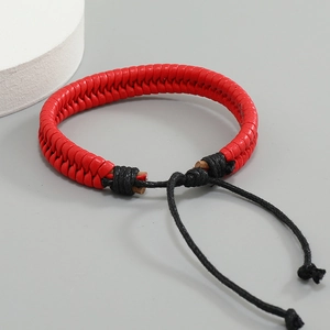 Detail of red hand-woven leather bracelet featuring black adjustable drawstring closure
