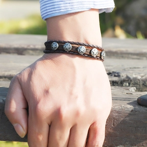 Close-up of brown braided leather bracelet featuring vintage silver pentagram star studs