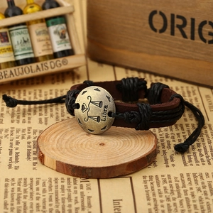 Detail of vintage Libra zodiac leather bracelet with bronze emblem on wooden surface