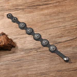 Détail d'un bracelet en cuir punk avec breloques crâne en métal et boutons-pression doubles