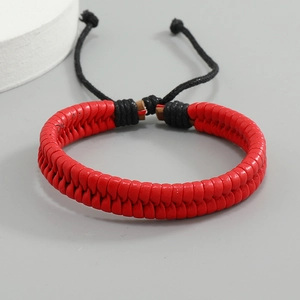 Close-up of red braided leather bracelet with black adjustable cords on neutral background