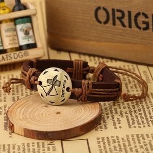 Detail of vintage Sagittarius leather bracelet on rustic wood and newspaper backdrop