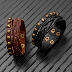 Detail of vintage multilayer braided leather bracelets with metallic rivets and snap buttons