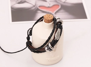 Detailed view of punk leather bracelet with silver wing pendant and beaded weave cords