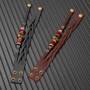 Macro detail of braided leather bracelets with skull charms and adjustable snap buttons