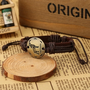 Close-up of Capricorn leather bracelet with bronze zodiac charm on vintage background