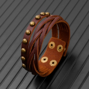 Detail of vintage brown braided leather bracelet with bronze rivets and metal snap buttons