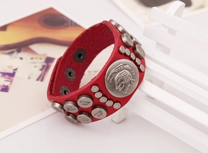 Détail d'un bracelet punk en cuir rouge orné de rivets argentés et médaillon tête de mort
