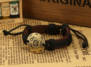 Close-up of retro leather Cancer zodiac bracelet with engraved bronze charm and braided cord