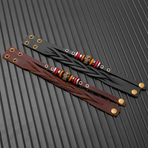 Detail view of woven leather bracelets with bronze skull charms and secure snap closures