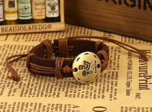 Detail of handwoven brown leather Aquarius zodiac bracelet with brass medallion and cord