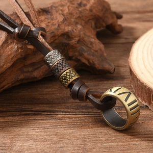 Close-up of vintage leather necklace with metallic geometric beads and Roman ring pendant