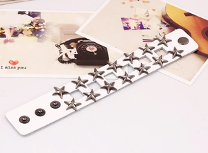 Dettaglio bracciale punk in pelle con borchie a stella, bottoni a pressione e fori quadrati
