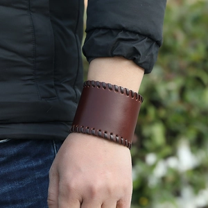 Close-up of brown leather cuff bracelet with hand-woven stitching and vintage texture