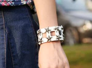 Dettaglio del bracciale in pelle bianca stile punk con borchie a stella e ritagli