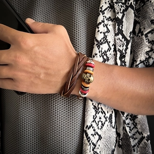 Macro shot of men's leather bracelet with antique bronze skull charm and braided cords