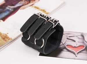 Detalle de pulsera punk de cuero negro con hebillas triples y anillos metálicos plateados
