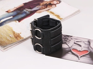 Detalle de brazalete punk de cuero con anillos metálicos y tres correas de hebilla
