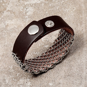 Dettaglio macro del bracciale in pelle marrone con maglia a catena argentata e bottone