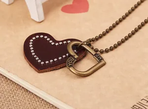Detail of vintage heart double pendants with leather texture and engraved metal tags