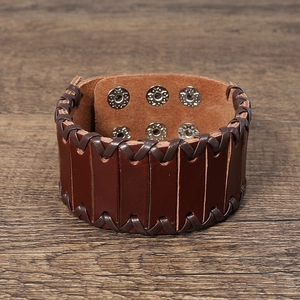 Detail of wide punk leather bracelet showing brown braided edges and adjustable metal snaps