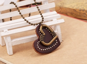 Close-up of vintage leather heart pendant with YOU and ME engraving and bronze ball chain