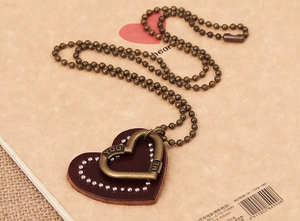 Detail of vintage heart leather pendant necklace with You Me engraving and bronze bead chain