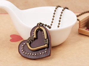 Macro shot of vintage leather heart pendant with YOU ME engraving on bronze metal