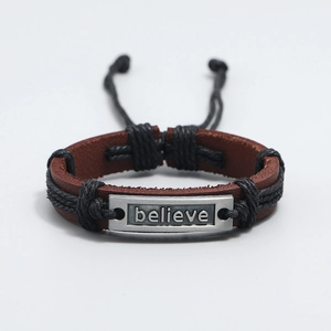 Detail of hand-braided brown leather bracelet with engraved silver believe plate