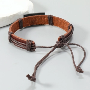 Macro view of braided brown leather bracelet with gray metal plate and adjustable cord