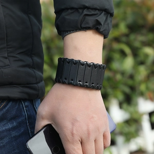 Detailed view of black wide leather bracelet with cross-stitch design on male wrist