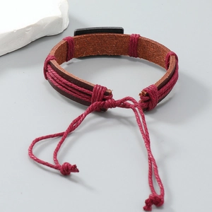 Dettaglio macro del bracciale in pelle intrecciata con piastra in lega e cordino regolabile