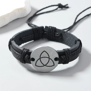 Close-up of braided black leather bracelet with vintage Celtic knot metal charm
