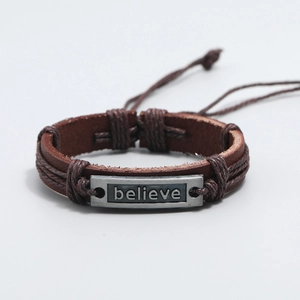 Macro view of woven leather bracelet with engraved believe metal plate and cord