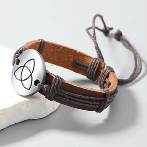 Detail of vintage braided leather bracelet featuring a metallic Triquetra knot ornament