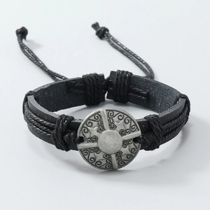 Detail of hand-woven black leather bracelet with embossed silver zinc alloy charm