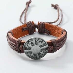 Detailed close-up of brown braided leather bracelet with vintage silver Celtic totem charm