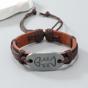 Close-up of handmade braided leather bracelet featuring an engraved fishbone metal charm