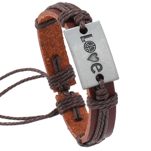 Vintage braided brown leather bracelet with Love peace metal plate on white background