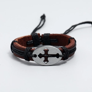 Dettaglio macro del bracciale in pelle intrecciata con ciondolo a croce e trama artigianale
